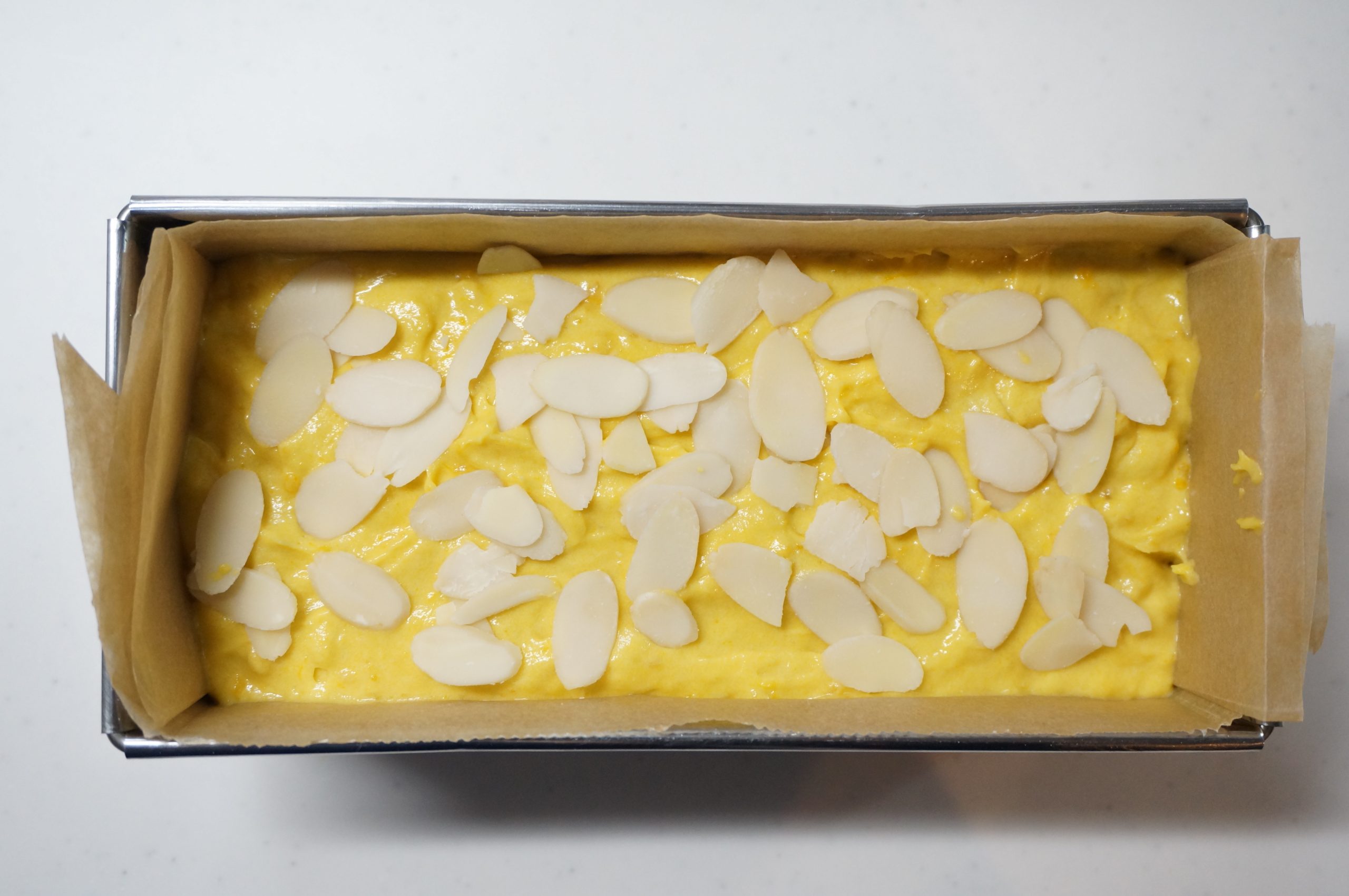 ペーパーをしいた型に流し入れ、表面をならす。アーモンドスライスをのせて、180℃のオーブンに10分入れる。