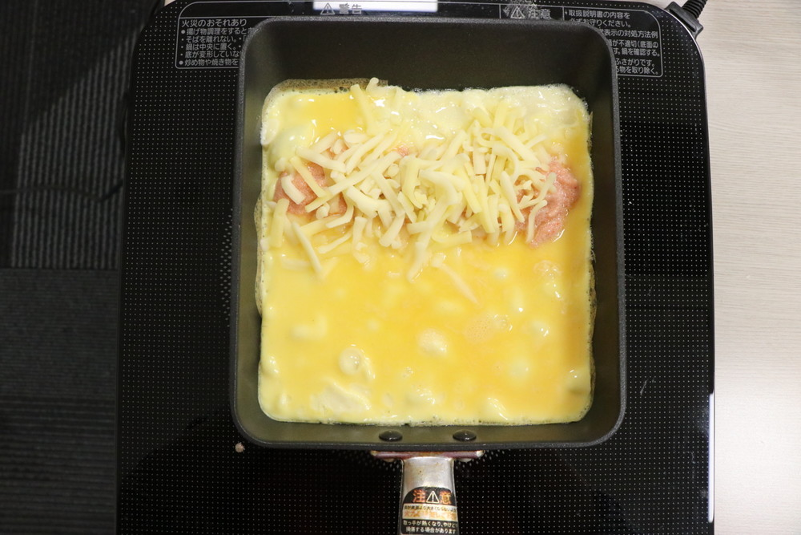 熱したフライパンに油をひき、卵液を流し込む。奥側に明太ソースとチーズをかける。