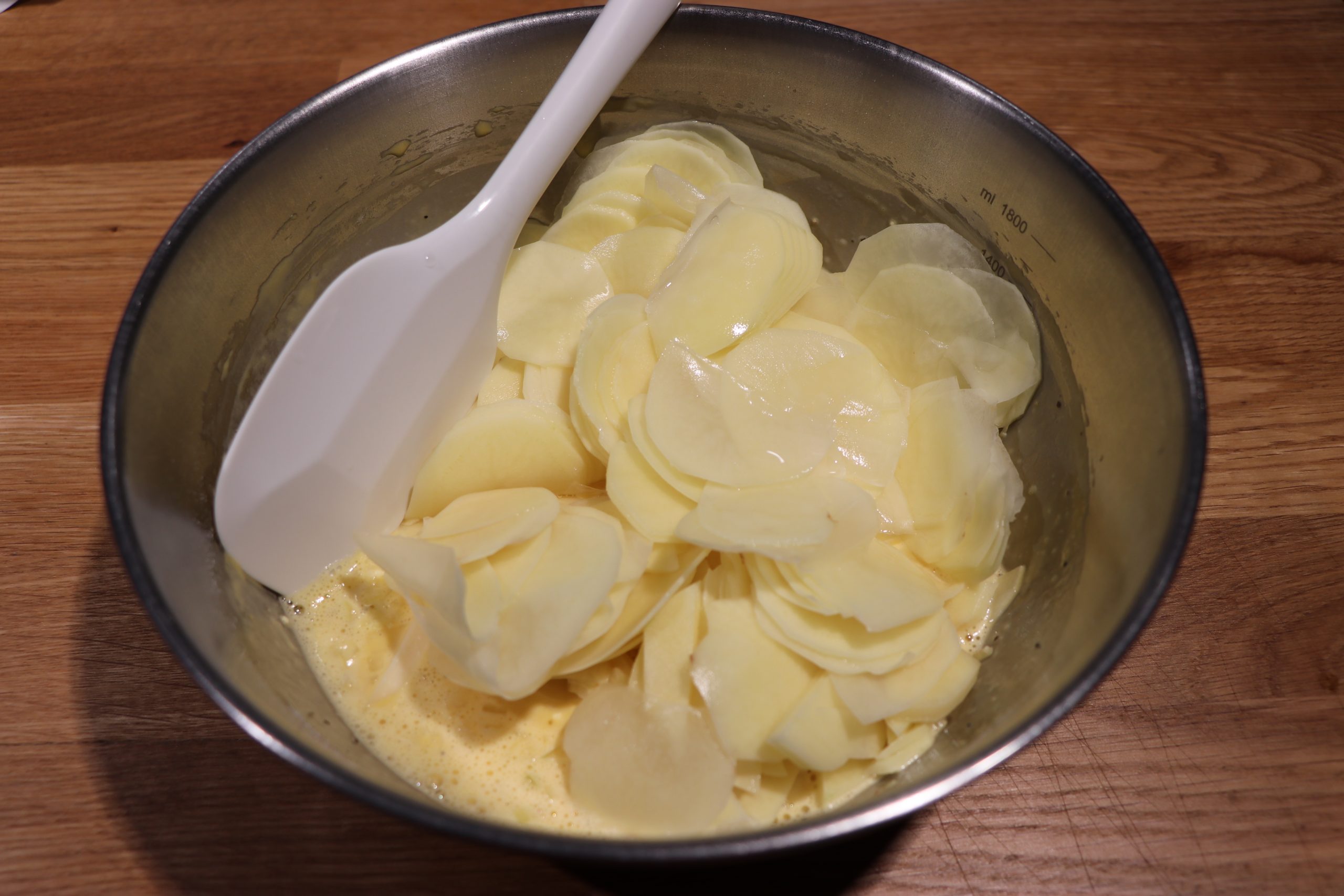 ゴムべらに持ち替え、スライスしたじゃがいもとみじん切りのたまねぎ、チーズを加えて、さっくり混ぜる。