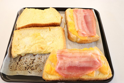 クッキングシートをひいた鉄板にパンを並べて、チーズとベーコンをのせる。
トースターで8分焼く。